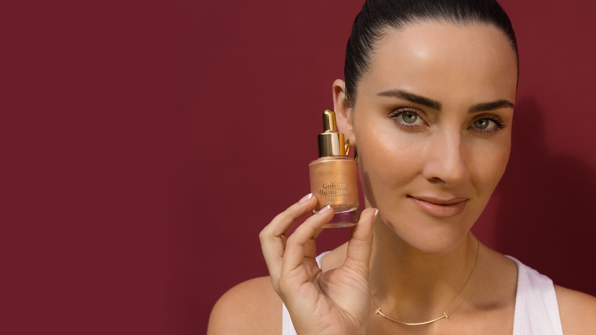 A woman holding a bottle of Eco By Sonya Golden Illuminiser - a sheer, luminous glow for face and body.