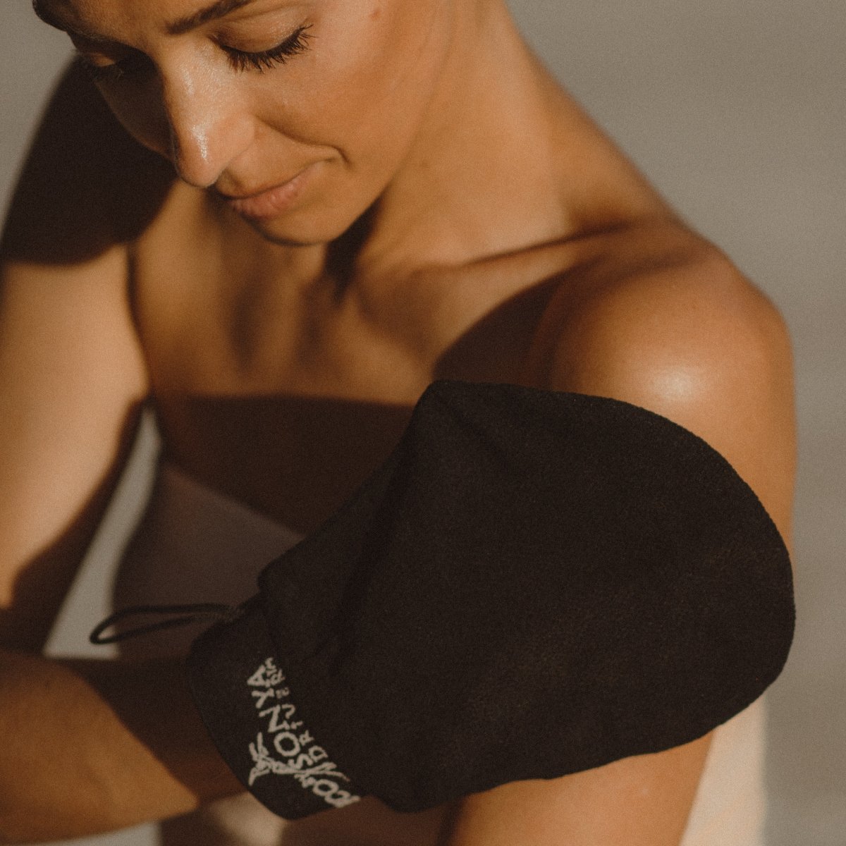 Woman using exfoliating glove on arm skin