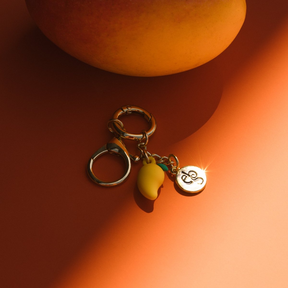 Keychain with mango charm and Eco by Sonya tag on an orange background