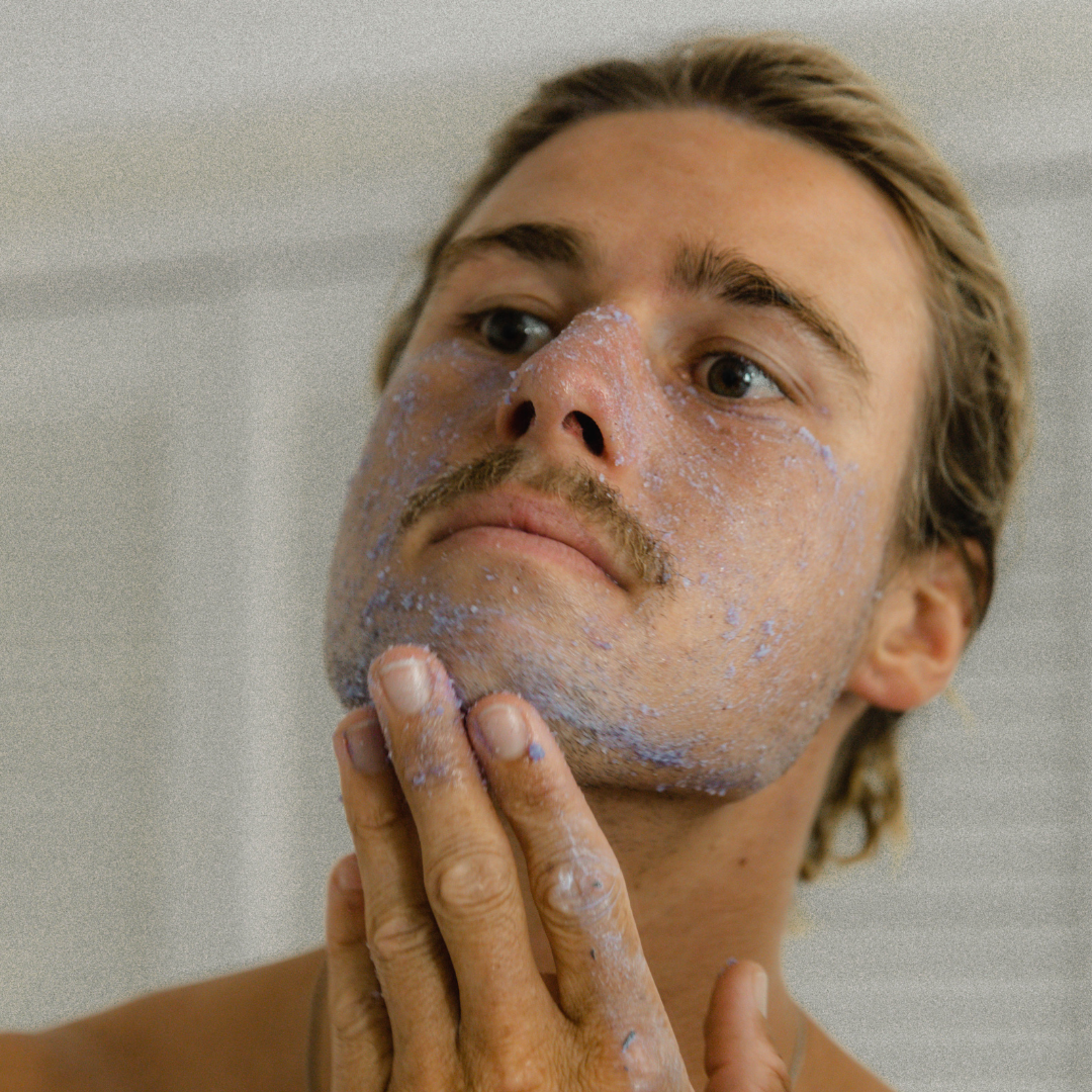 Man applying purple Super Acai Exfoliator with a neutral background